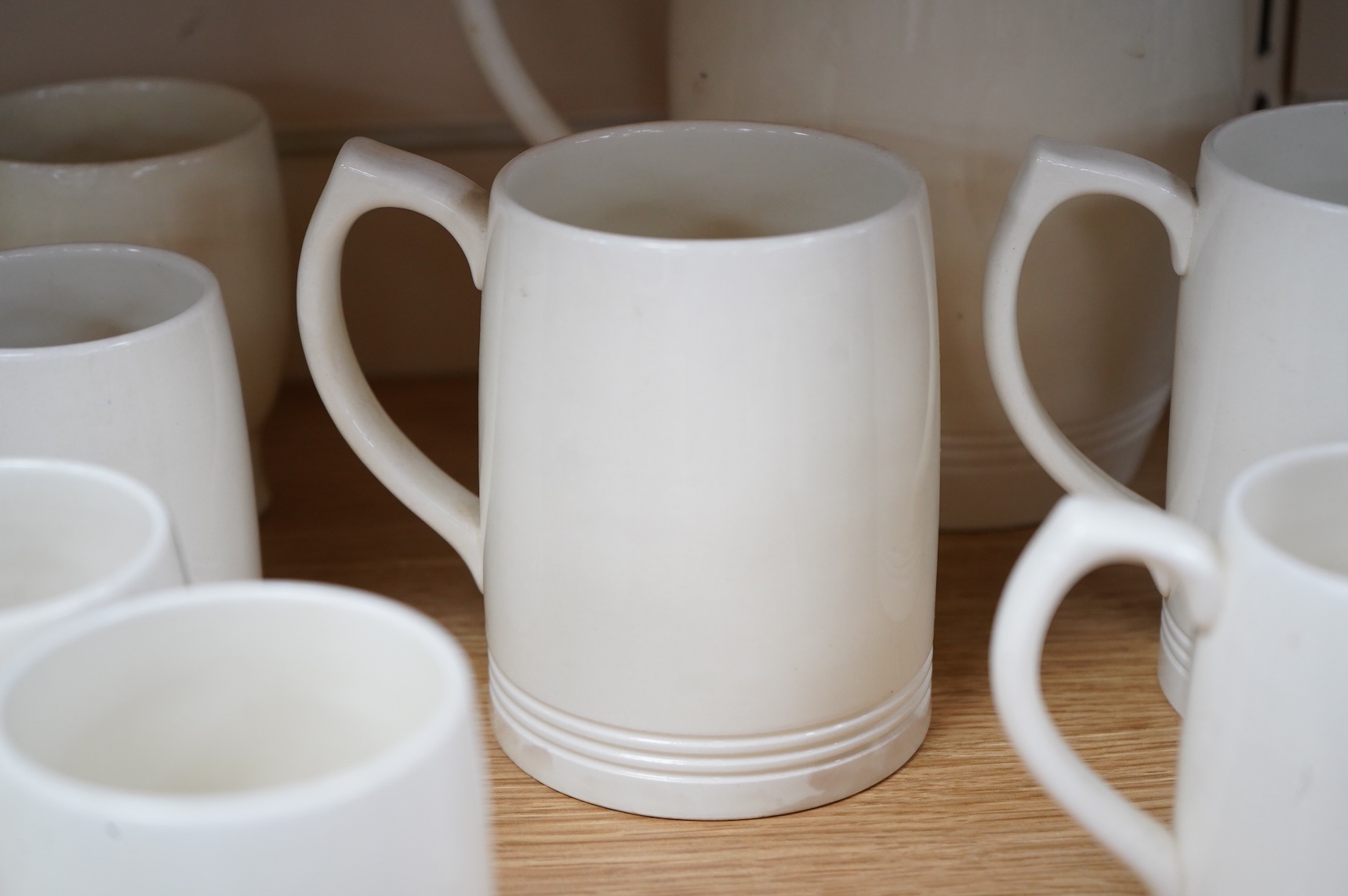 Keith Murray for Wedgwood, a cream lemonade jug, five small mugs, two large three faceted, largest 21cm high (12)